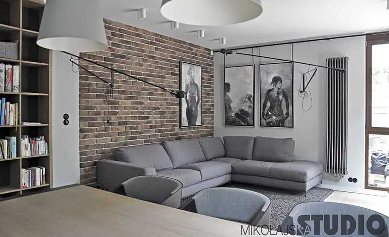 Salon z ceglaną ścianą z ciekawymi lampami natynkowymi