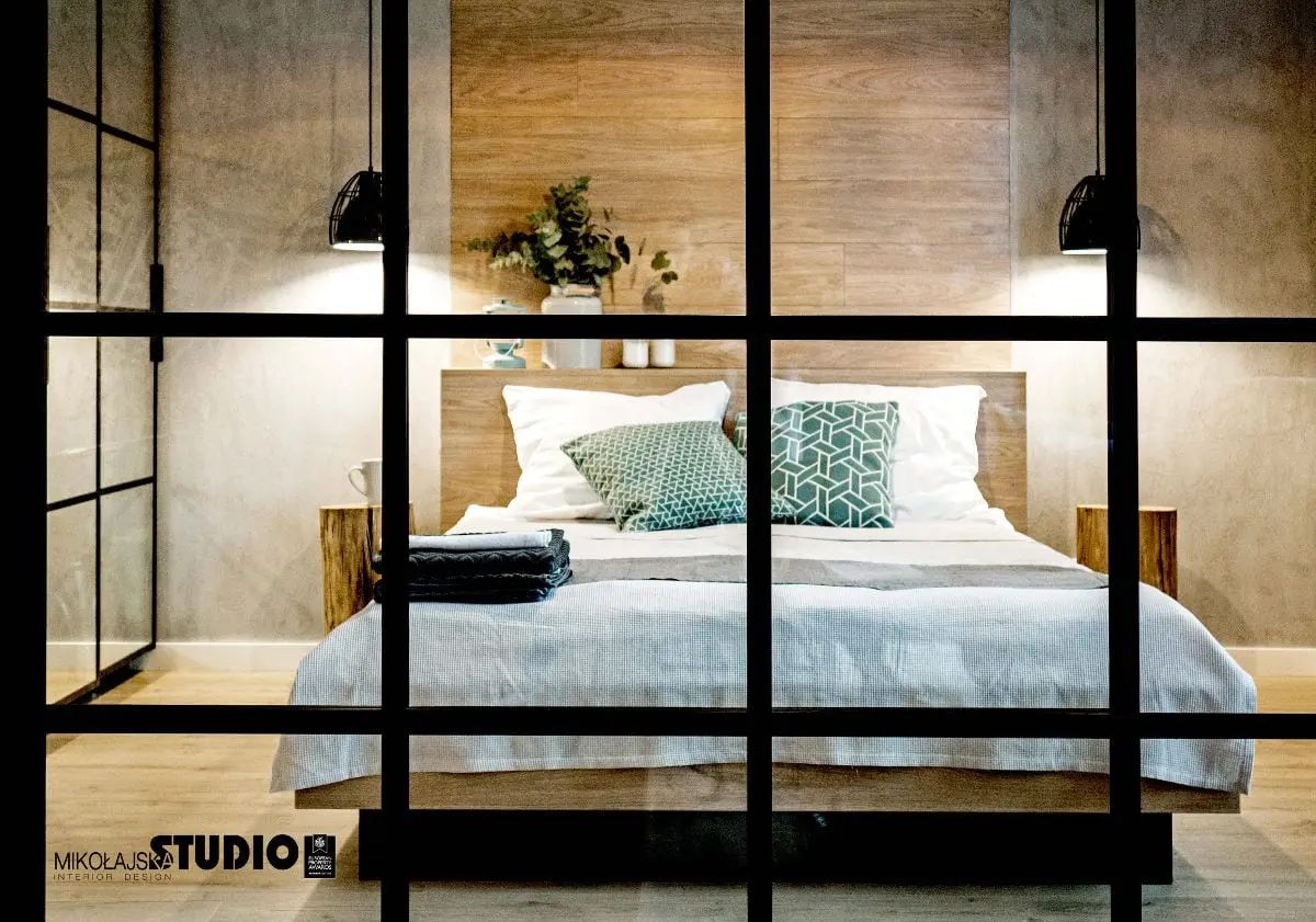 Widok na sypialnię za industrialnym przeszkleniem, proj. Mikołajska Studio