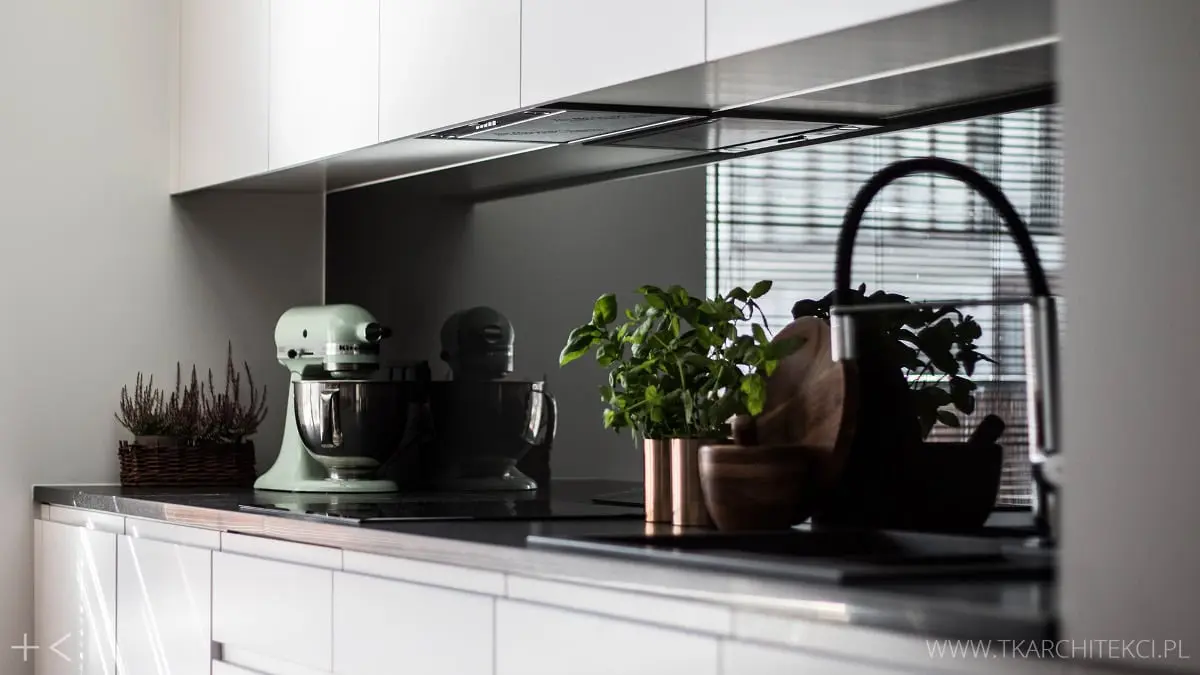 Białe meble kuchenne z czarną ścianą nad blatem | proj. TK Architekci
