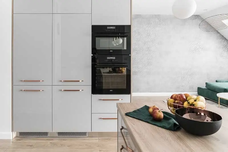 Meble kuchenne z popielatymi frontami na wysoki połysk i złotymi uchwytami | proj. Studio Projekt (zdjęcie: Fotomohito)