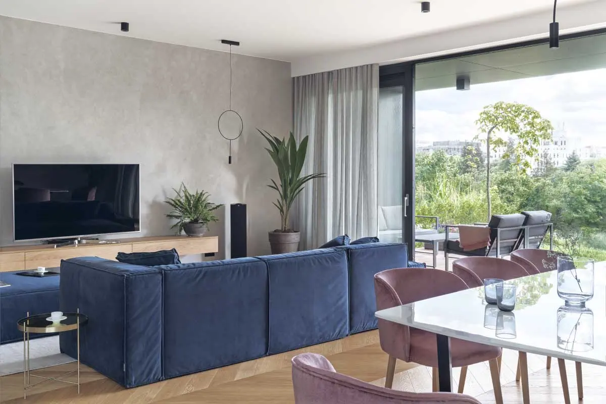 Betonowa ściana w salonie pięknie kontrastuje z przytulnym aksamitem na meblach | proj. luumo., zdj. Tom Kurek