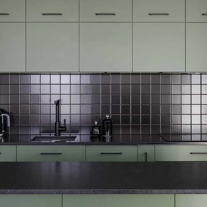 Czarne płytki nad blatem pięknie odbijają światło. | Proj. AWAW; Fot: Michał Młynarczyk