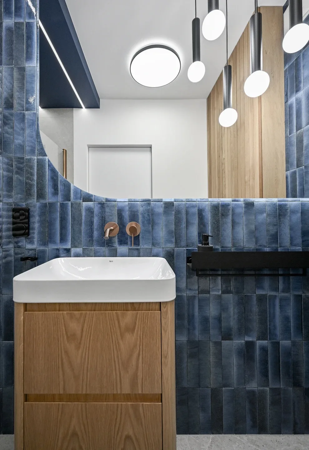 granatowa łazienka z drewnem i złotą armaturą
